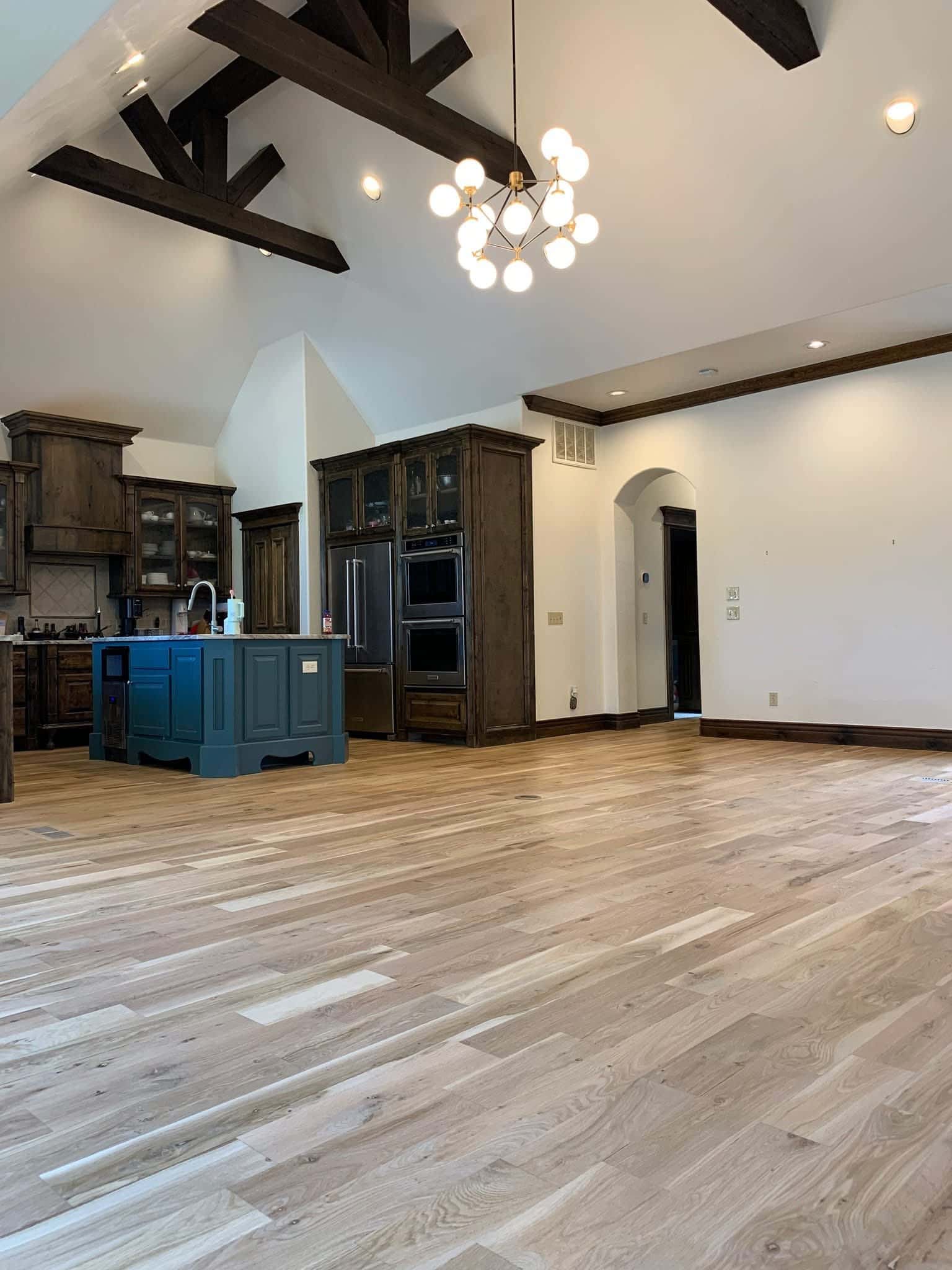 Vaulted ceiling home addition with exposed timber beams and light oak hardwood floors.