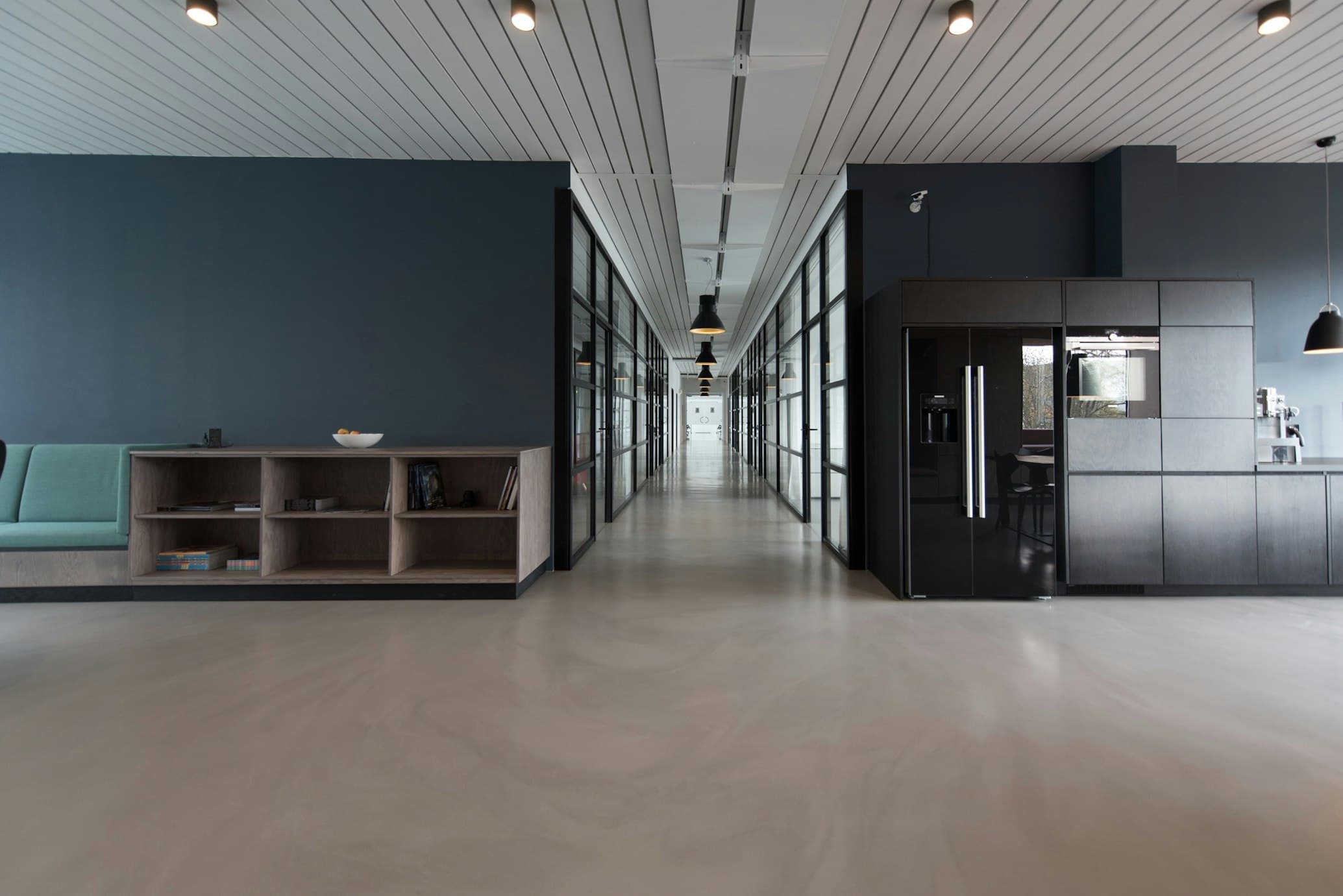 Corporate office hallway displaying smooth light-grey poured epoxy floor and glass wall partitions